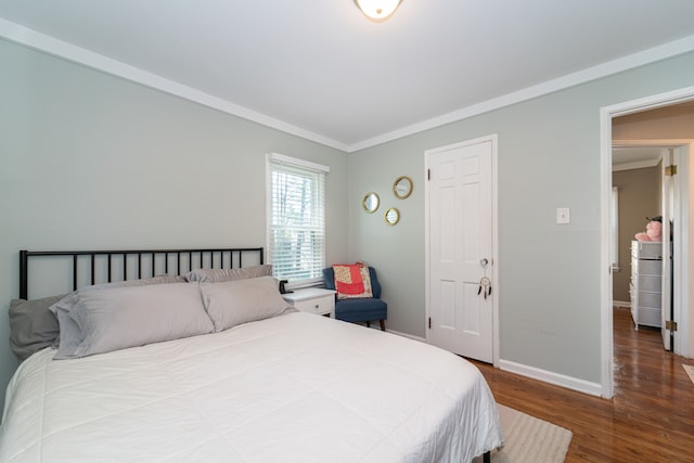 bedroom with wood finished floors, baseboards, and crown molding