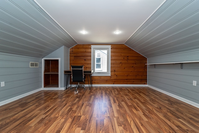 additional living space featuring vaulted ceiling, baseboards, wood finished floors, wooden walls, and an office area
