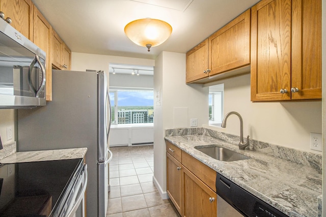 555 E William St Unit 25I, Ann Arbor, MI 48104 - kitchen with stainless steel appliances, a sink, light tile patterned floors, light stone counters, and brown cabinets