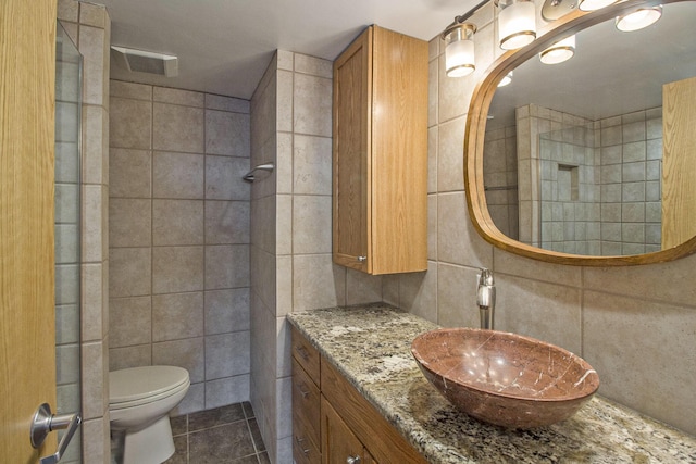 555 E William St Unit 25I, Ann Arbor, MI 48104 - bathroom with tile walls, a tile shower, toilet, tile patterned flooring, and vanity