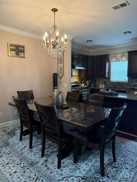 11702 Weingartz E, Utica, MI 48315 - dining area featuring a chandelier, ornamental molding, and baseboards