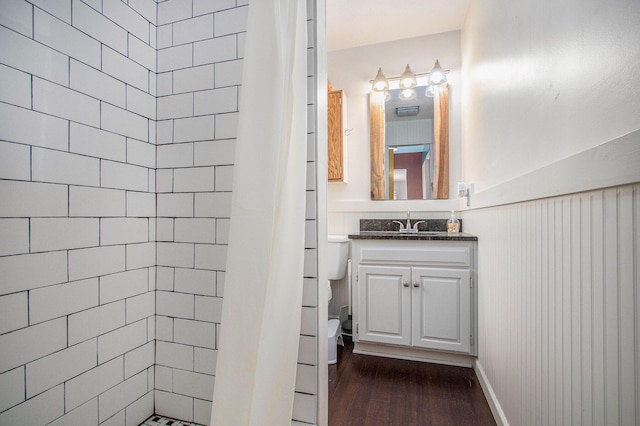 bathroom with vanity, a tile shower, toilet, and wood finished floors