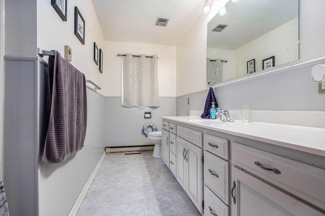 full bath with tile walls, toilet, a baseboard radiator, vanity, and a wainscoted wall