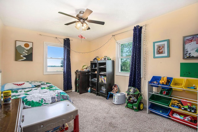 carpeted bedroom featuring multiple windows and ceiling fan