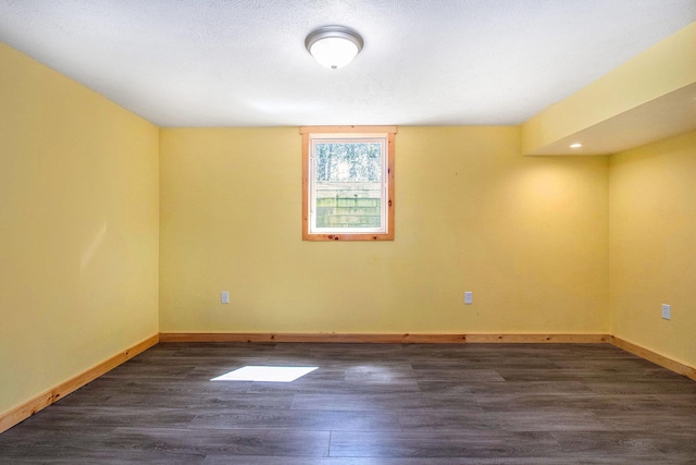 spare room featuring dark wood-style floors and baseboards