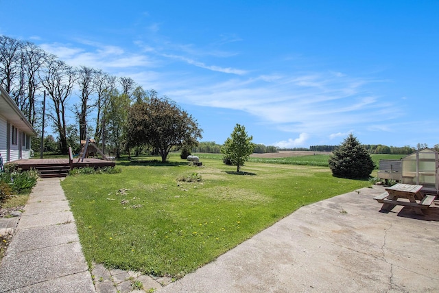 view of green lawn with a patio and a deck