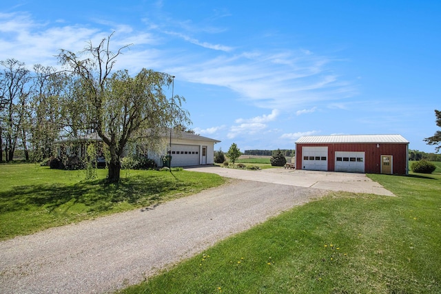 view of front of house with a front yard, driveway, an outbuilding, and a detached garage