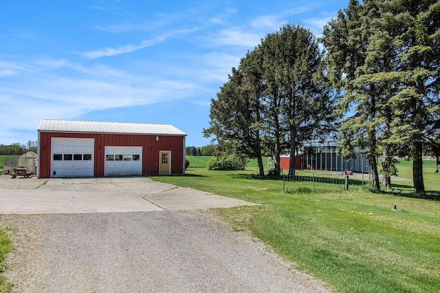 view of green lawn featuring a garage and an outbuilding