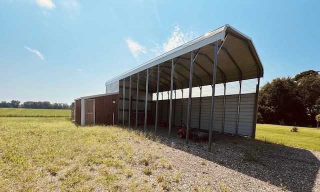 view of outdoor structure featuring a detached carport, dirt driveway, and an outbuilding