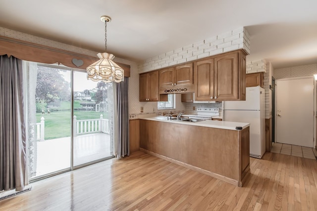 841 Driburg Dr, Commerce Twp, MI 48390 - kitchen with freestanding refrigerator, a peninsula, a chandelier, brown cabinets, and light countertops