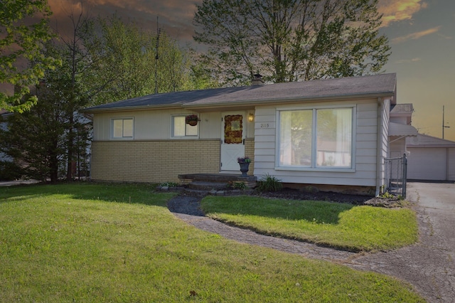 view of front of house featuring a front yard, brick siding, and a detached garage