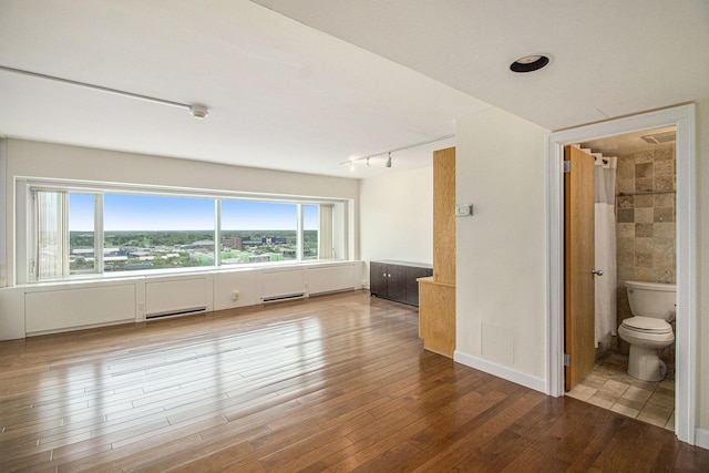 555 E William St Unit 25J, Ann Arbor, MI 48104 - spare room featuring track lighting, wood finished floors, and baseboard heating
