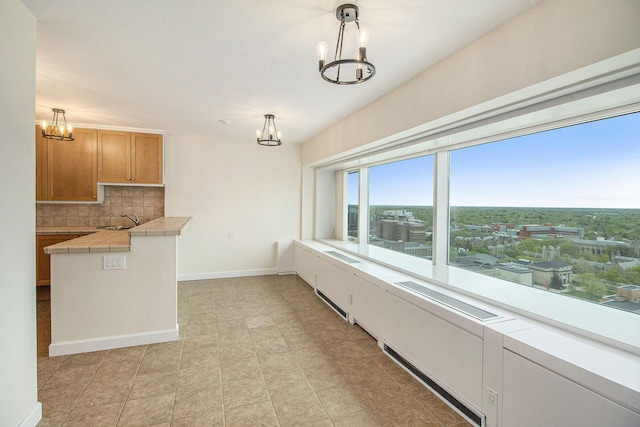 555 E William St Unit 25J, Ann Arbor, MI 48104 - unfurnished dining area with a chandelier, a sink, and baseboards