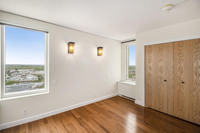 555 E William St Unit 25J, Ann Arbor, MI 48104 - unfurnished bedroom featuring wood finished floors, baseboards, and a closet