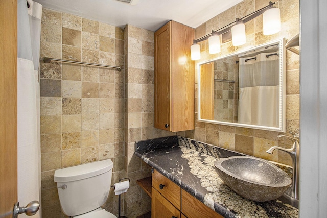 555 E William St Unit 25J, Ann Arbor, MI 48104 - bathroom with tile walls, vanity, toilet, a shower with shower curtain, and backsplash