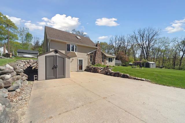 5780 Elvira, Pinckney, MI 48169 - view of side of property with a storage unit, an outbuilding, a lawn, a chimney, and a patio area
