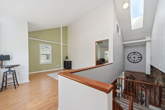 5780 Elvira, Pinckney, MI 48169 - hall with high vaulted ceiling, a skylight, wood finished floors, baseboards, and an upstairs landing