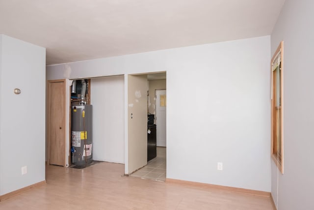 unfurnished bedroom with water heater, light wood-type flooring, two closets, and baseboards
