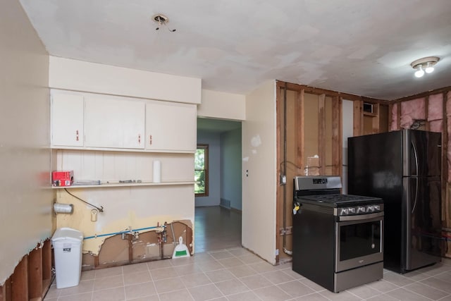 kitchen with stainless steel range with gas cooktop, freestanding refrigerator, and white cabinets