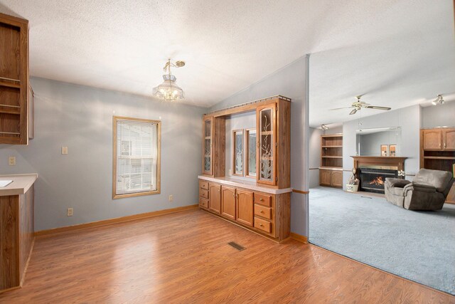 12346 Quail Ct, Shelby Twp, MI 48315 - dining space featuring lofted ceiling, a glass covered fireplace, ceiling fan, light wood-style flooring, and a chandelier