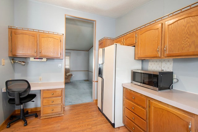 12346 Quail Ct, Shelby Twp, MI 48315 - kitchen with stainless steel microwave, white fridge with ice dispenser, light countertops, light wood-style flooring, and a textured ceiling
