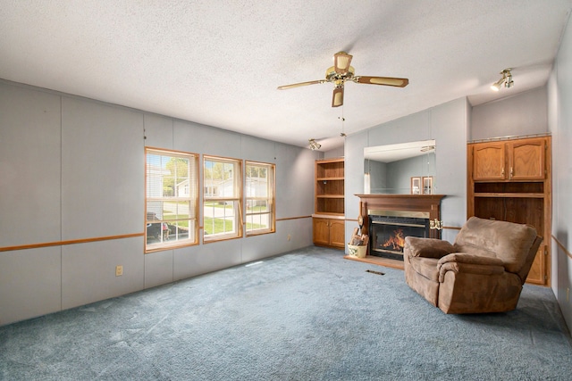 12346 Quail Ct, Shelby Twp, MI 48315 - carpeted living area with a glass covered fireplace, a ceiling fan, a textured ceiling, and vaulted ceiling