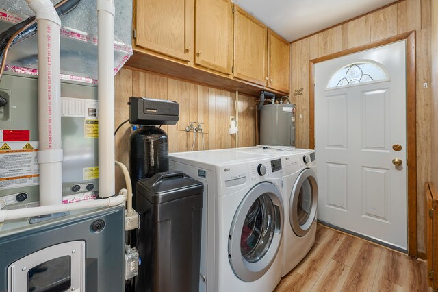 8607 Cochise Ct, Howard City, MI 49329 - laundry area with cabinet space, washer and dryer, light wood-style flooring, electric water heater, and wooden walls