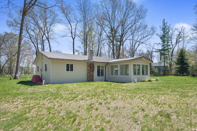 8607 Cochise Ct, Howard City, MI 49329 - rear view of property featuring a chimney, a lawn, and metal roof