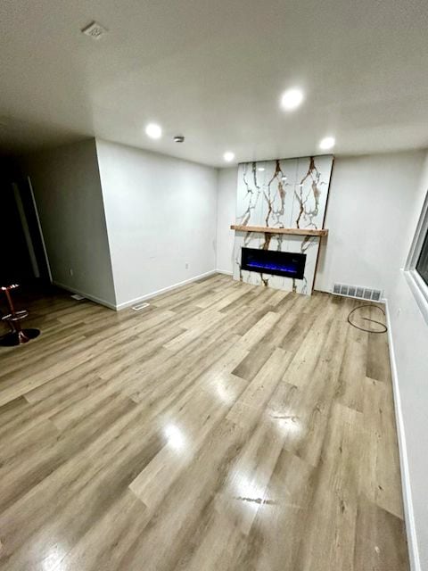unfurnished living room with wood finished floors, recessed lighting, a fireplace, and baseboards