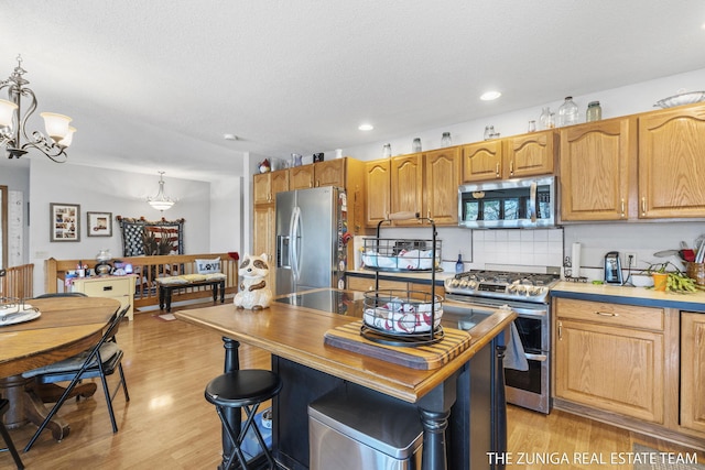 1087 Shore Walk Ln, Whitehall, MI 49461 - kitchen with stainless steel appliances, a chandelier, recessed lighting, hanging light fixtures, and light wood-style floors