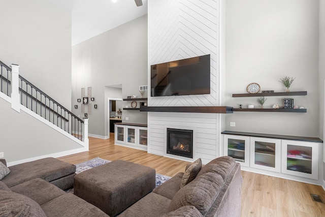 5414 Bradley Ct, Kalamazoo, MI 49009 - living area featuring wood finished floors, a towering ceiling, stairs, a fireplace, and baseboards