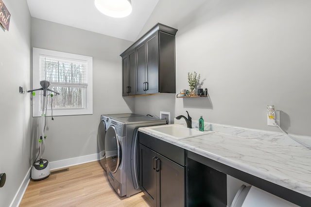 5414 Bradley Ct, Kalamazoo, MI 49009 - clothes washing area featuring cabinet space, separate washer and dryer, light wood-style floors, and baseboards
