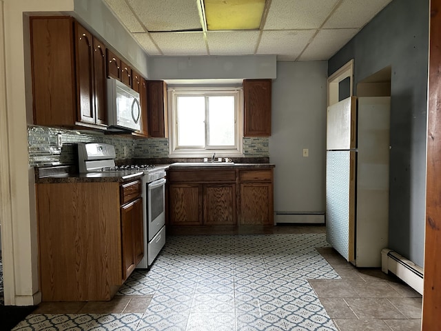117 Hanover Ct, Hanover, MI 49241 - kitchen featuring white appliances, a baseboard radiator, dark countertops, a paneled ceiling, and decorative backsplash