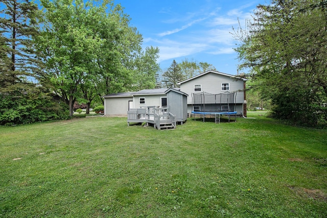 7055 N Center Rd, Mount Morris, MI 48458 - rear view of property featuring a trampoline, a wooden deck, and a lawn