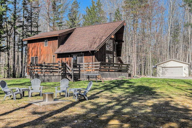 2526 Aikens Rd, Manistee, MI 49660 - view of front of house with a deck, a shingled roof, a detached garage, and a front lawn