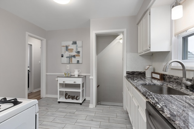 kitchen with a sink, dishwasher, white cabinetry, dark stone counters, and white electric range