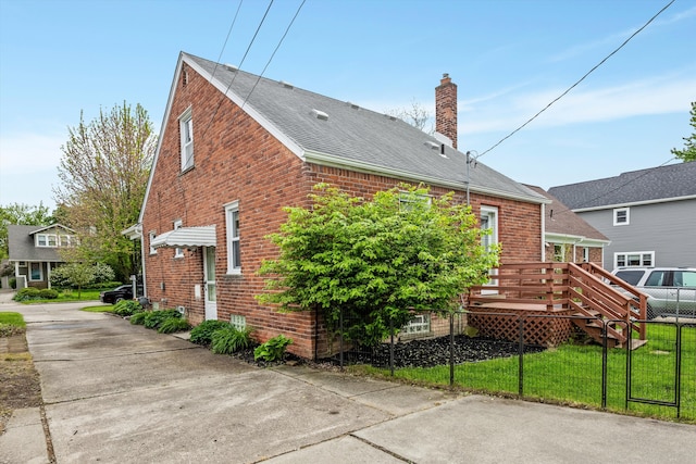 rear view of house featuring brick siding, a chimney, fence, a shingled roof, and a deck