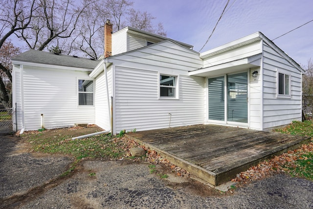 rear view of property featuring a wooden deck and a chimney