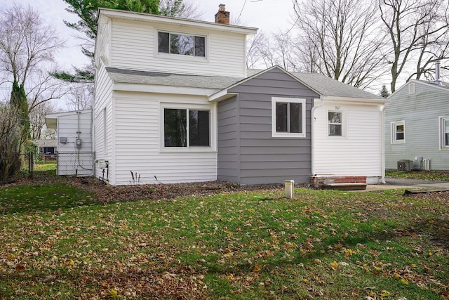 rear view of property with a chimney, central air condition unit, and a shingled roof