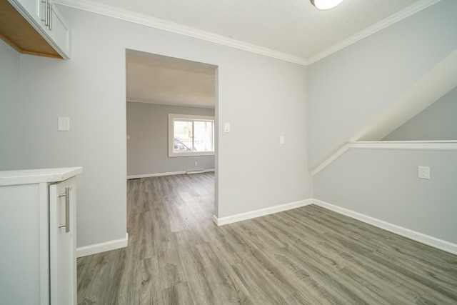 unfurnished room with light wood-type flooring, baseboards, and crown molding