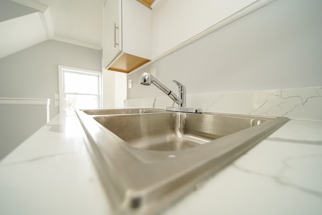 kitchen view of a sink, white cabinetry, and light countertops