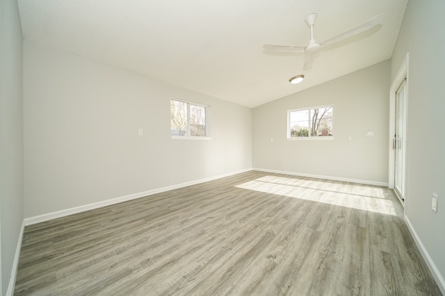 spare room with light wood finished floors, plenty of natural light, lofted ceiling, baseboards, and a ceiling fan