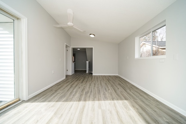 spare room featuring light wood finished floors, vaulted ceiling, baseboards, and a ceiling fan
