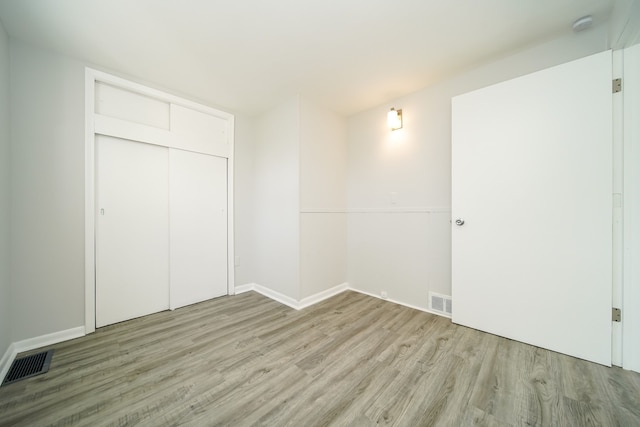unfurnished bedroom featuring light wood-style floors, baseboards, and a closet