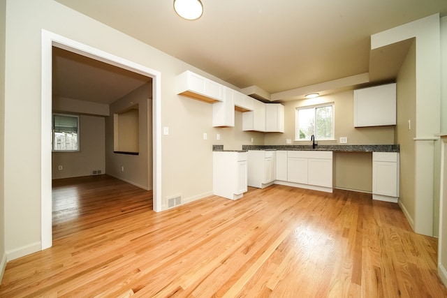 28407 Milton Ave, Warren, MI 48092 - kitchen featuring dark countertops, white cabinets, light wood-type flooring, a sink, and baseboards