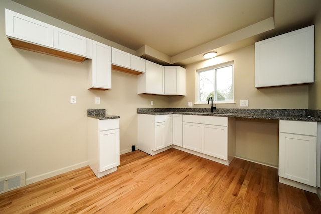 28407 Milton Ave, Warren, MI 48092 - kitchen with a sink, light wood-style flooring, white cabinetry, dark stone counters, and baseboards