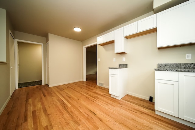 28407 Milton Ave, Warren, MI 48092 - kitchen featuring light wood finished floors, white cabinets, dark stone counters, and baseboards