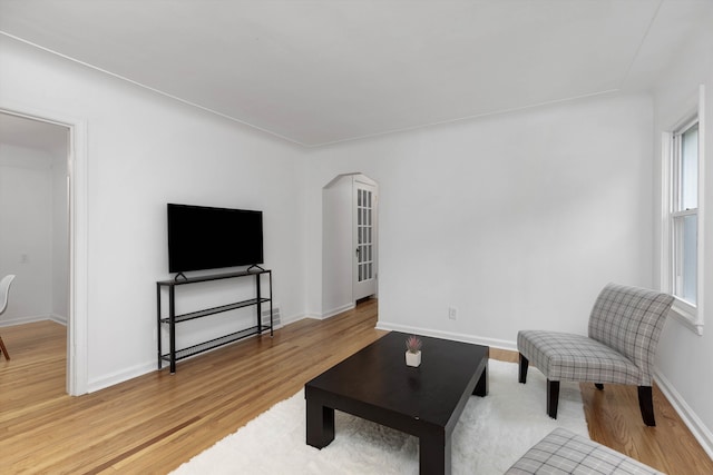 living room featuring light wood-style flooring, arched walkways, and baseboards
