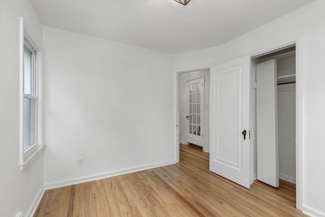 unfurnished bedroom featuring light wood-style floors, baseboards, and multiple windows