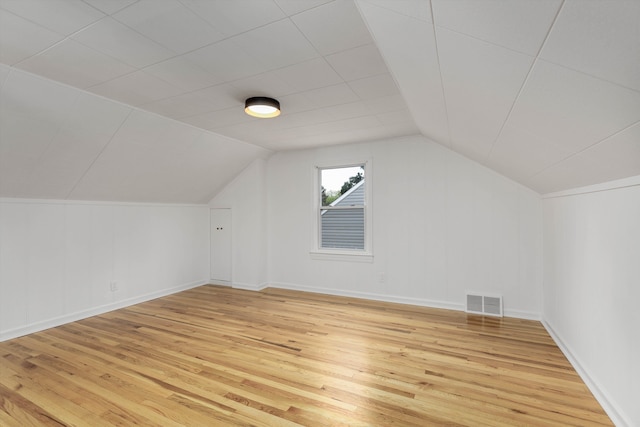 bonus room featuring light wood-style flooring, lofted ceiling, and baseboards